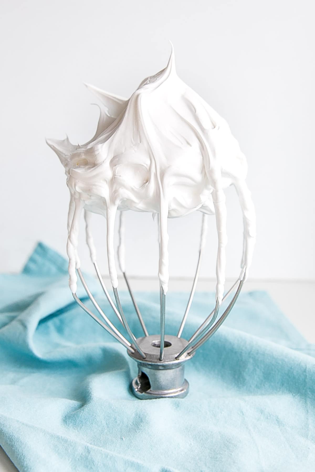 This old-fashioned 7 minute frosting recipe is light, delicious, and easy to make. A bright white frosting that's perfect for cakes, cupcakes, and more. | livforcake.com 7 minute frosting shown on a stand mixer whisk.