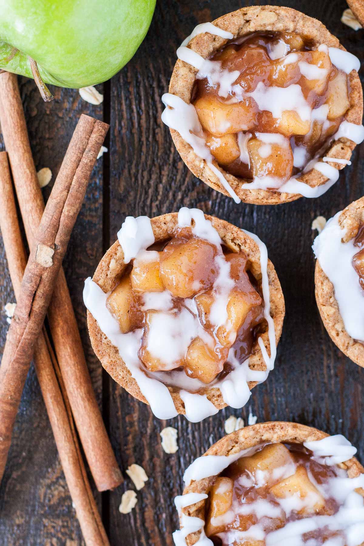 These Apple Crisp Cookie Cups combine classic oatmeal cookies with homemade apple pie filling for the perfect comfort food. | livforcake.com Overhead photo of the cookie cups with a sugar glaze drizzled on them.