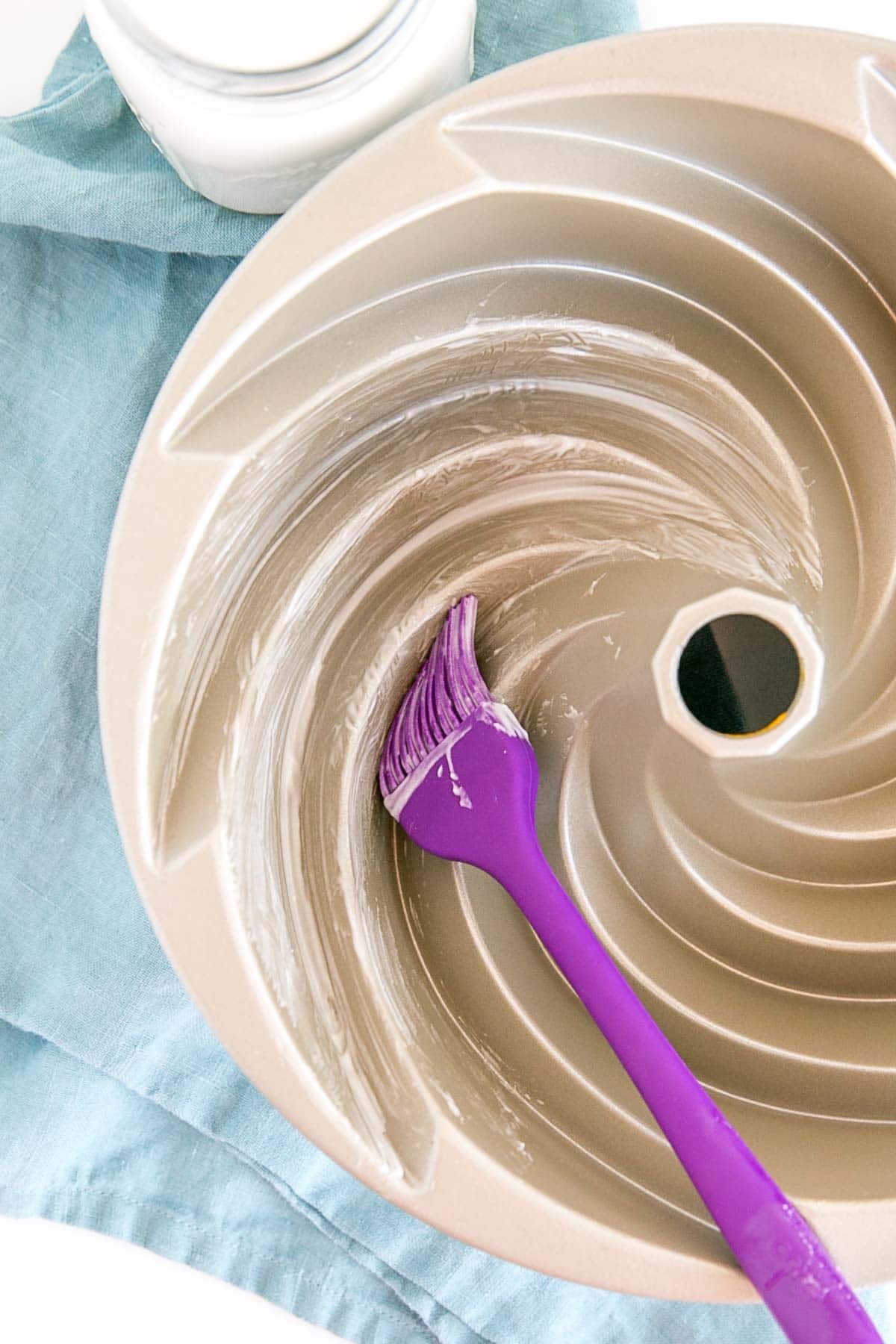 Brushing pan release into the nooks and crannies of a bundt pan.