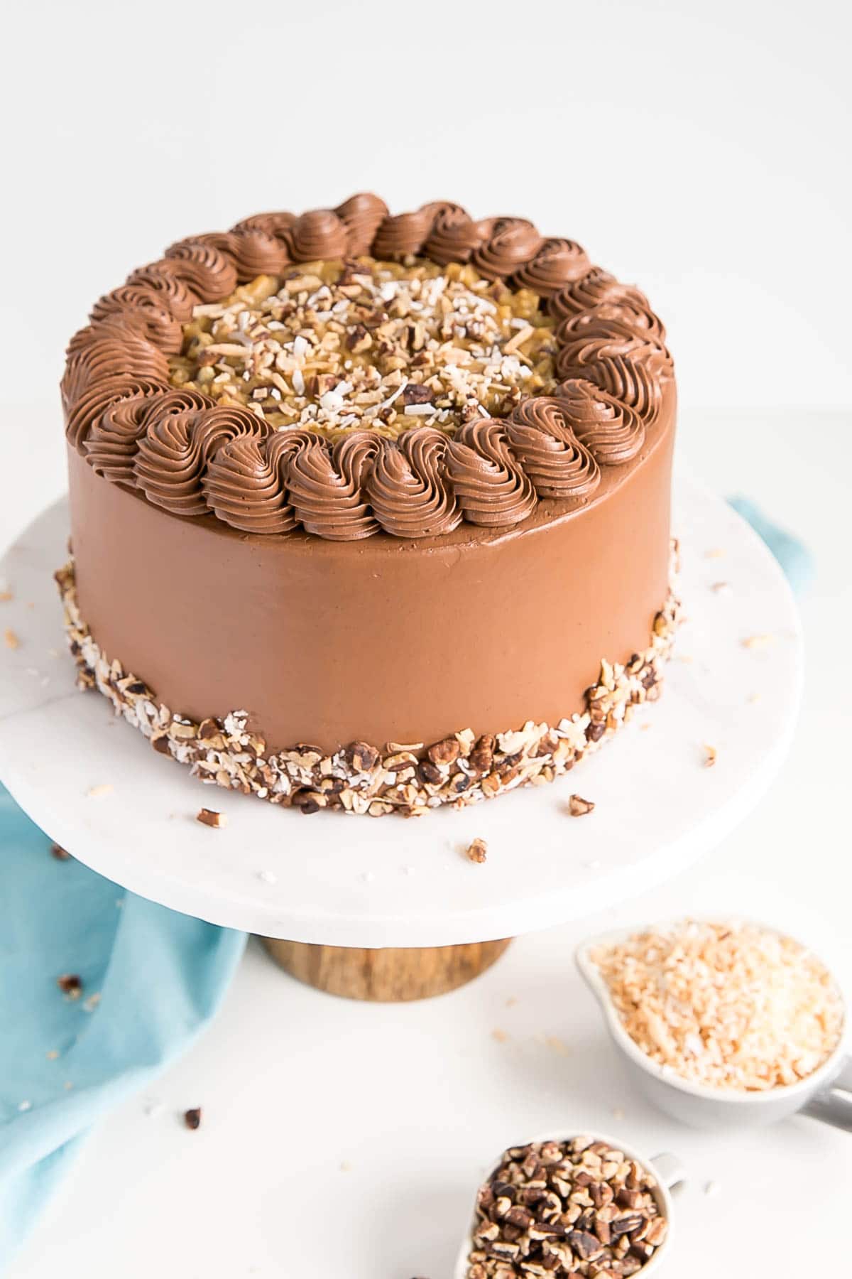 This Classic German Chocolate Cake combines rich chocolate cake layers with a sweet coconut pecan filling and a dreamy chocolate buttercream. | livforcake.com Angled shot of the cake showing the top filled in with the pecan filling.