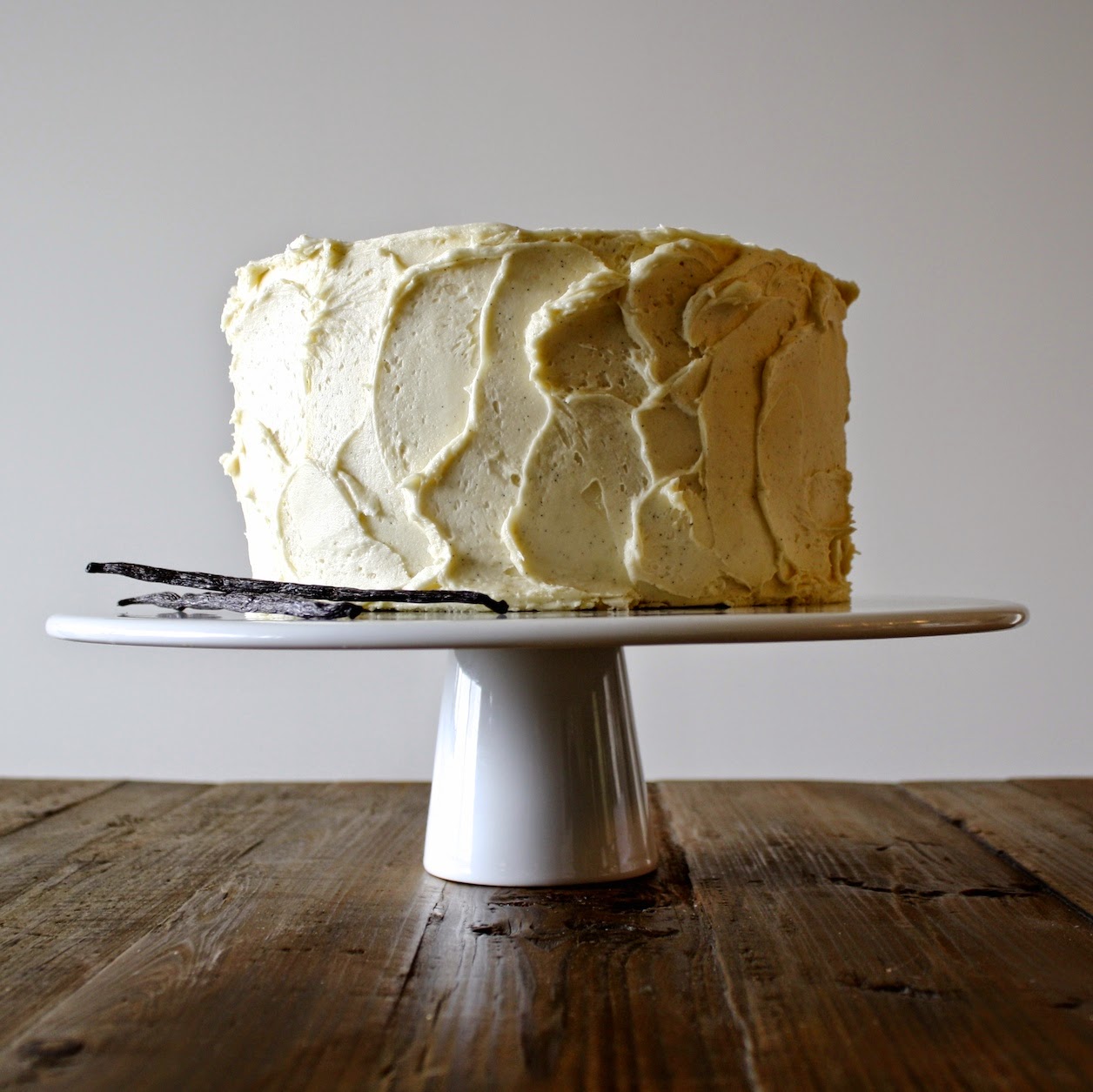 A cake on a white cake stand sitting on top of a wooden table