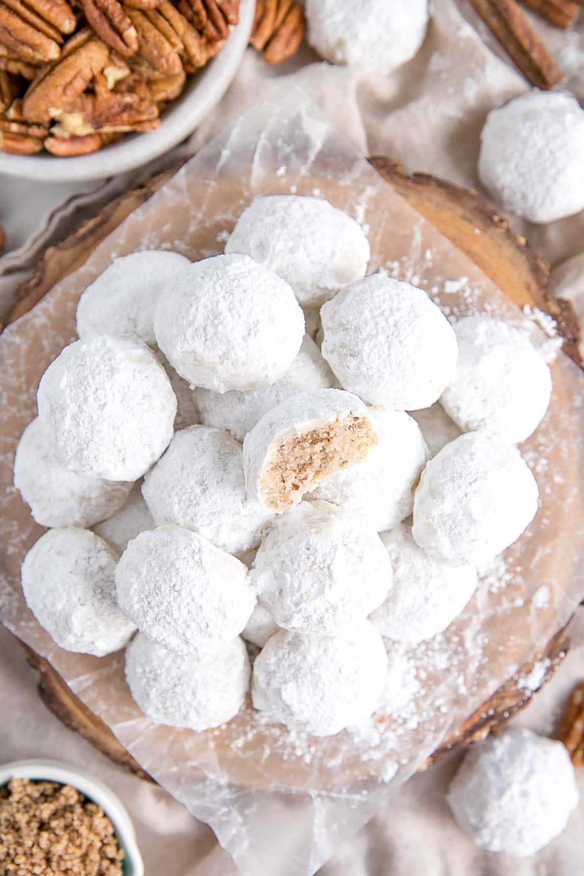 These Mexican Wedding Cookies (also known as Snowball Cookies or Russian Tea Cakes) are buttery, melt-in-your-mouth delicious! Pecan cookies with a hint of cinnamon dusted with powdered sugar. | livforcake.com Overhead photo of the stacked snowball cookies on a plate.