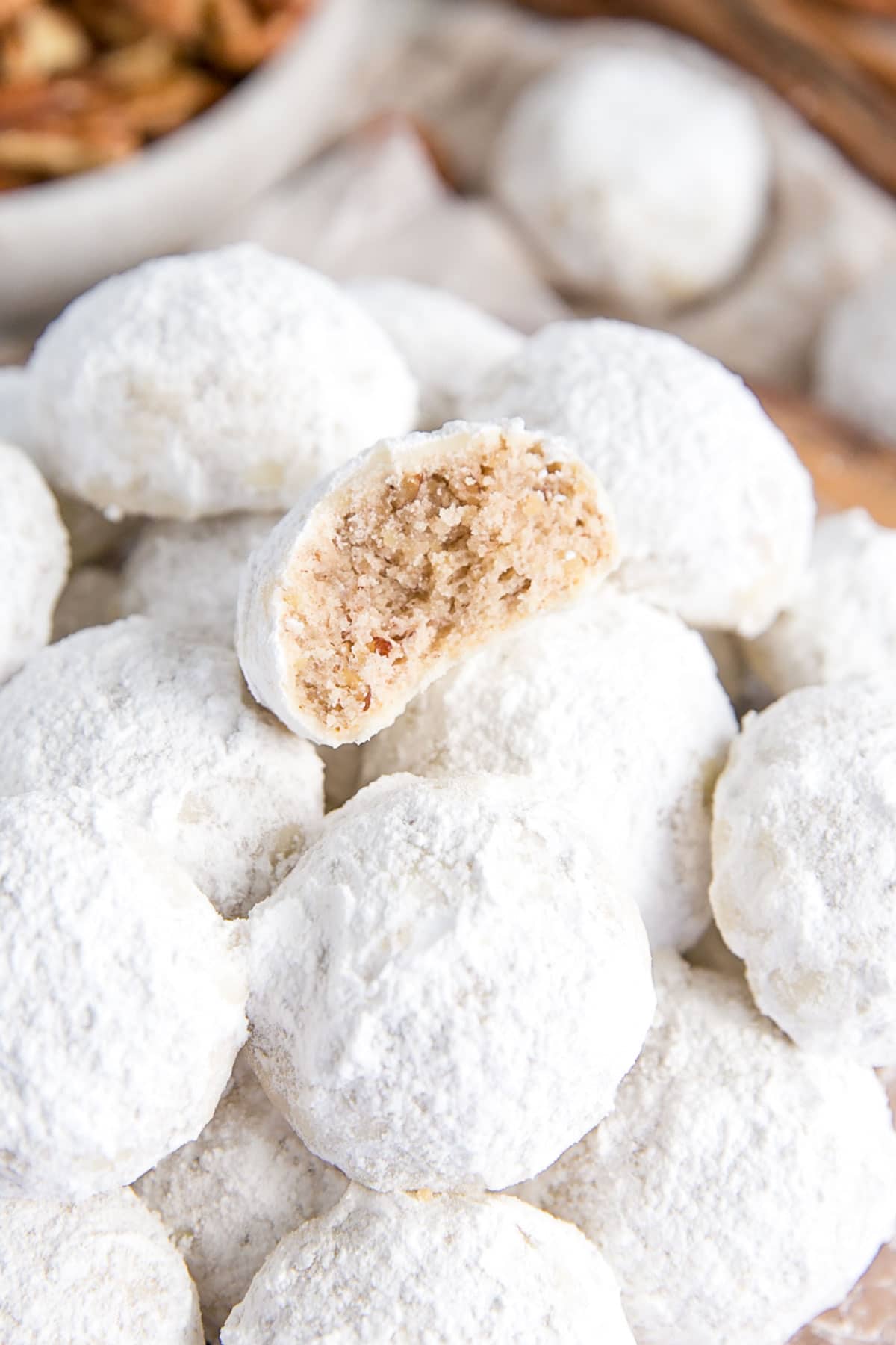 These Mexican Wedding Cookies (also known as Snowball Cookies or Russian Tea Cakes) are buttery, melt-in-your-mouth delicious! Pecan cookies with a hint of cinnamon dusted with powdered sugar. | livforcake.com Close up of a cookie with a bite taken out.