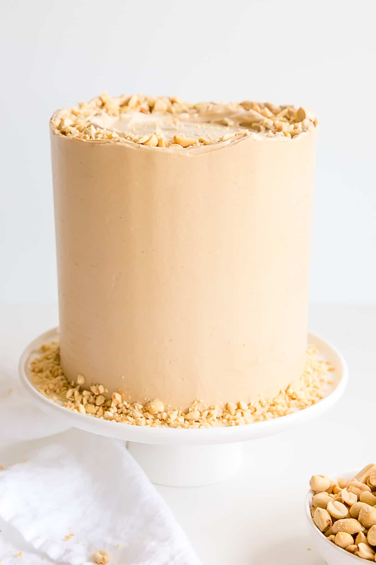 Peanut butter lovers, this cake is for you! Peanut butter cake layers studded with peanut butter chips covered in a peanut butter Swiss meringue buttercream. | livforcake.com Peanut butter cake with fresh chopped peanuts.