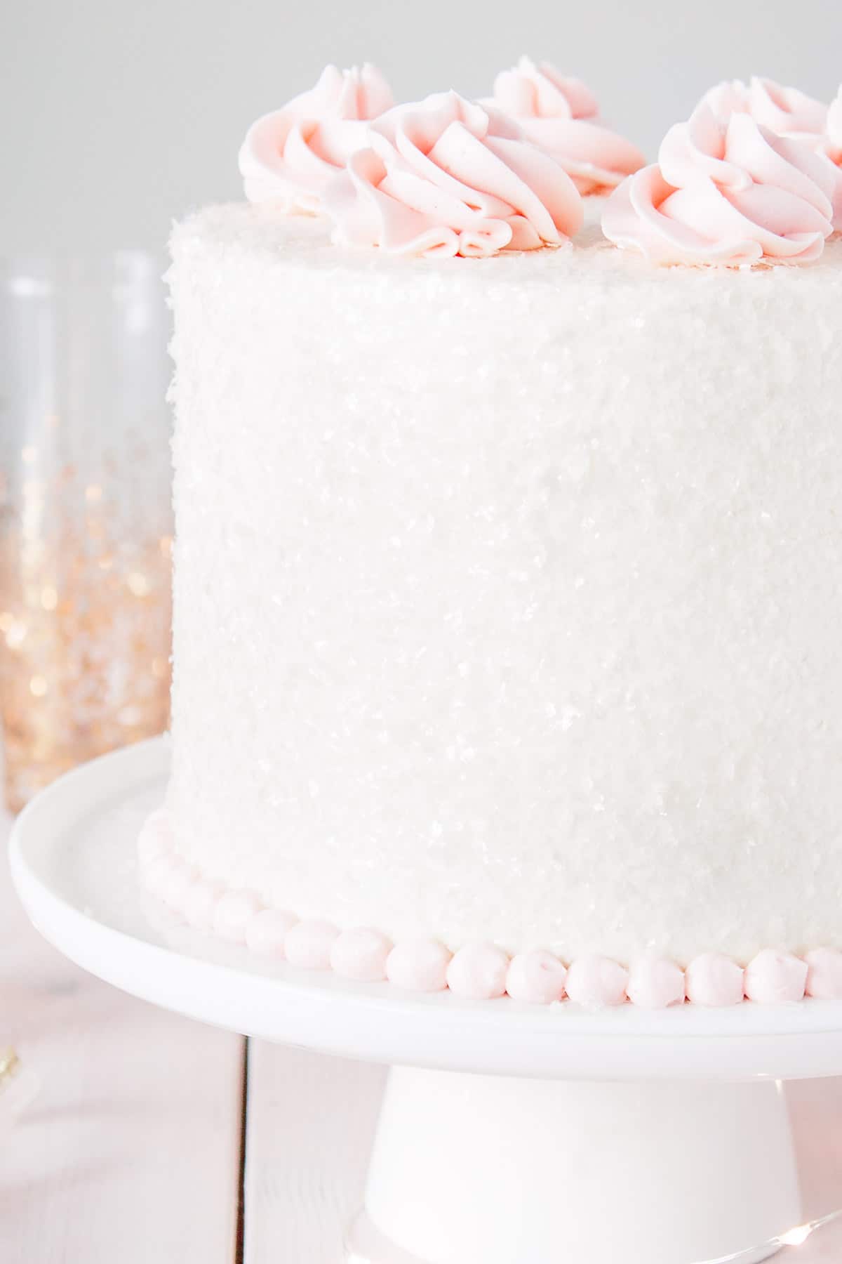 This Pink Champagne Cake is the perfect way to celebrate any occasion or holiday! A champagne infused cake with a classic vanilla buttercream. | livforcake.com Close up of cake sparkles on a pink champagne cake.