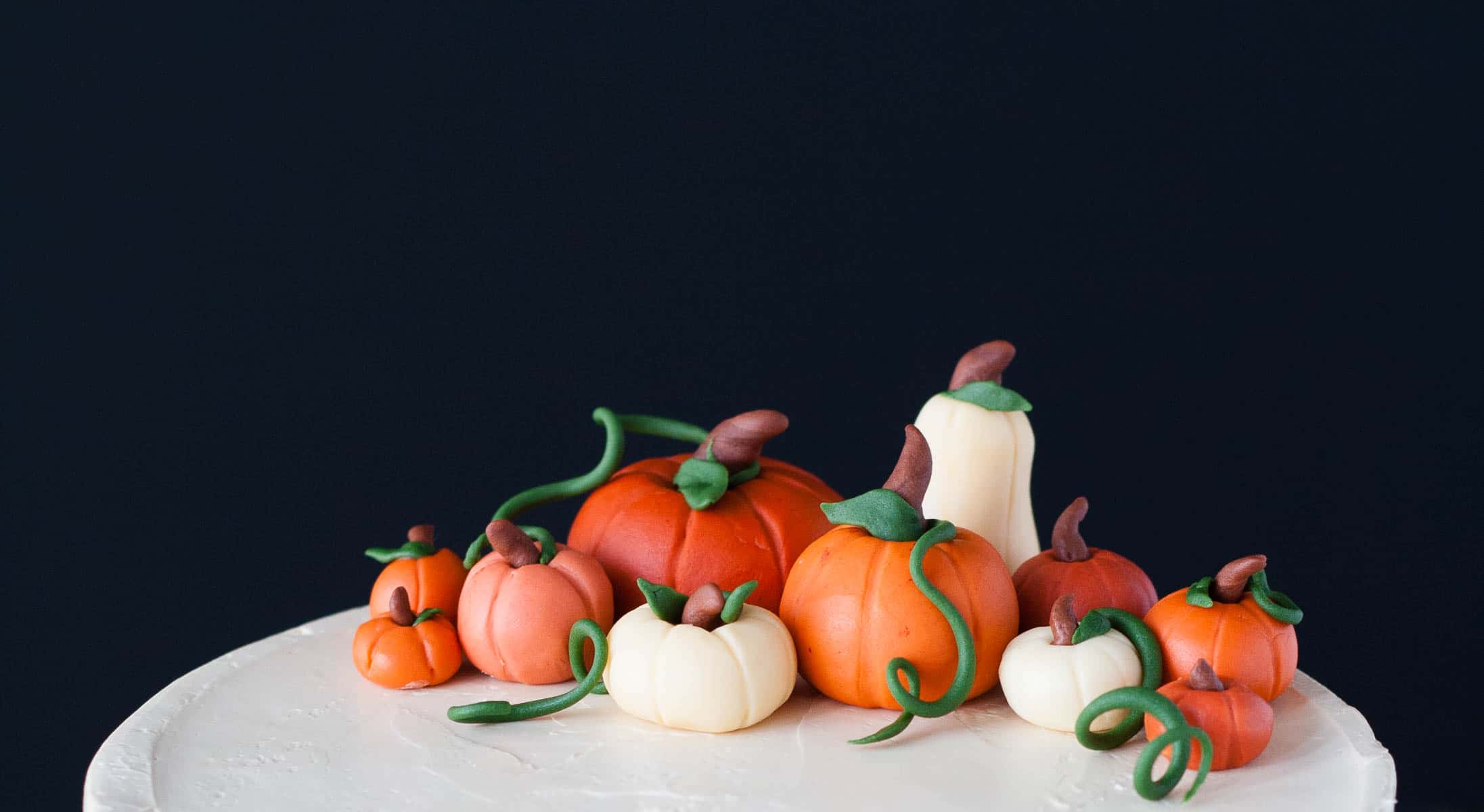 This Pumpkin Spice Latte Cake is your favorite Fall beverage in cake form! Pumpkin spice cake with an espresso buttercream. | livforcake.com Close up of fondant pumpkins