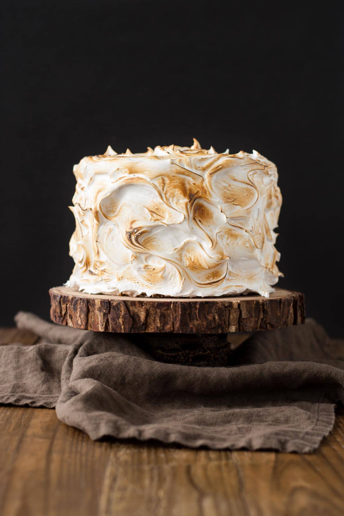 This old-fashioned 7 minute frosting recipe is light, delicious, and easy to make. A pure white frosting that's perfect for a variety of delicious desserts. | livforcake.com Picture of a S'mores Cake covered in meringue that is torched.