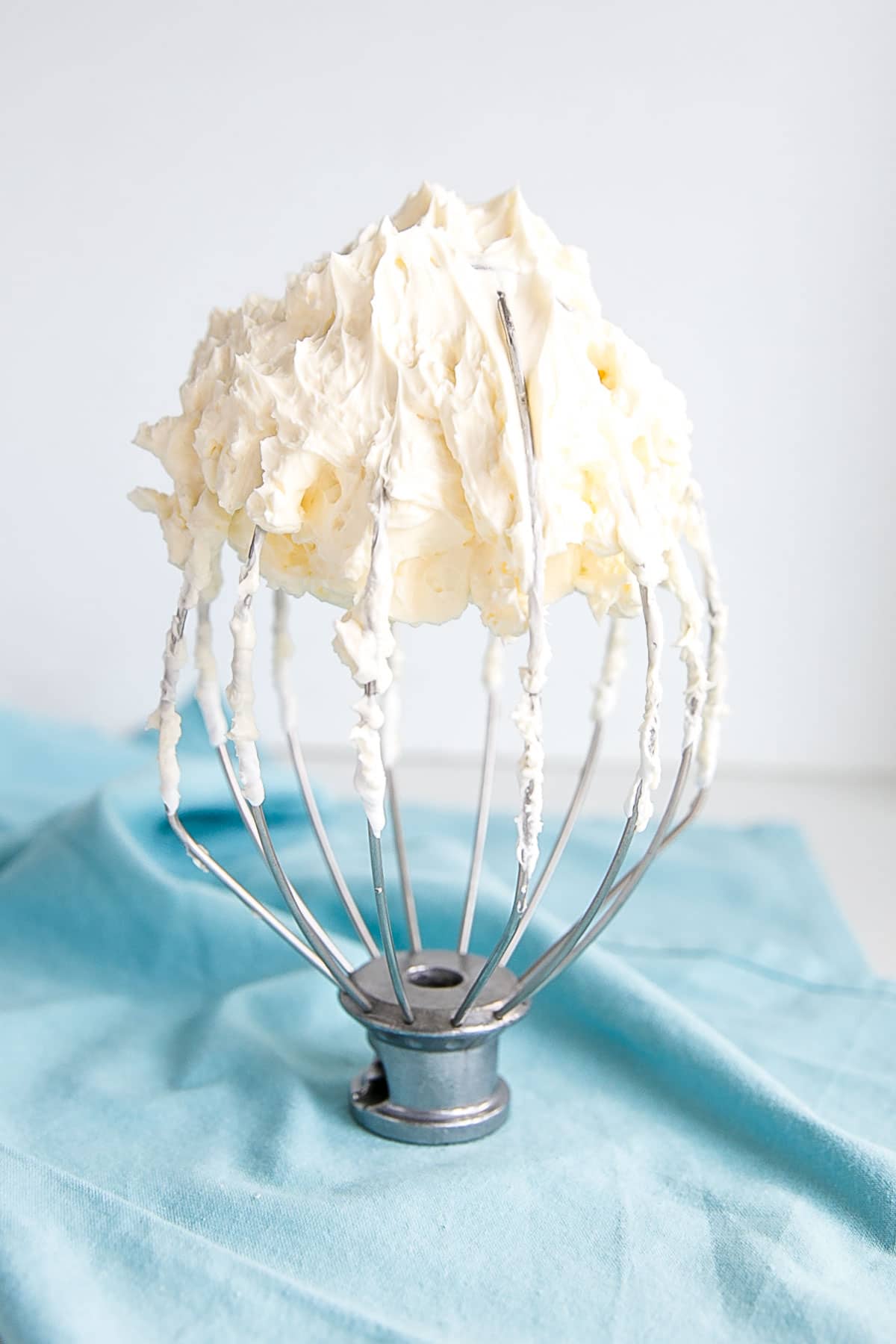This tutorial on how to make Swiss Meringue buttercream is the only resource you'll need to make the smoothest, silkiest frosting! | livforcake.com Swiss meringue buttercream on a whisk different angle.