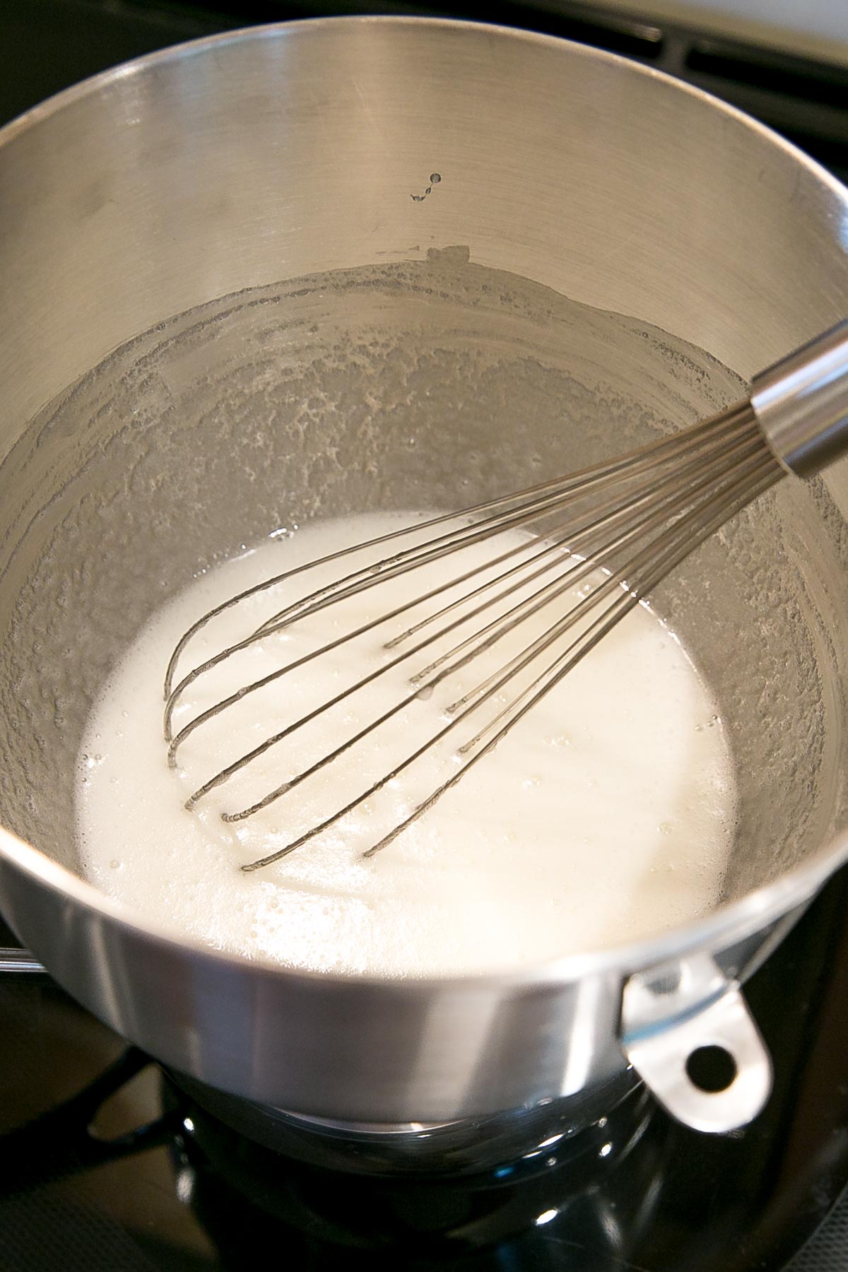 This tutorial on how to make Swiss Meringue buttercream is the only resource you'll need to make the smoothest, silkiest frosting! | livforcake.com Whisking egg whites and sugar in a bowl over a simmering pot of water.
