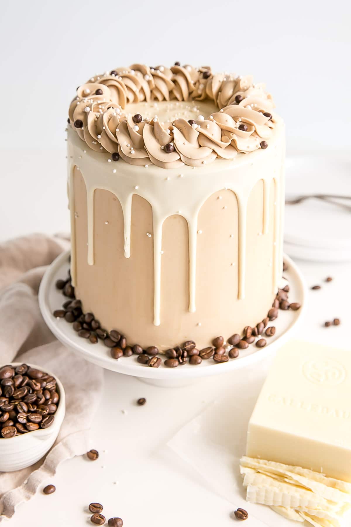 Angled shot of the cake with chopped white chocolate and coffee beans in the foreground.